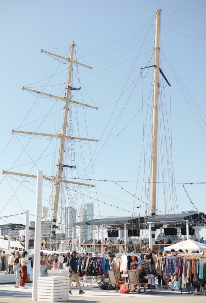 outdoor market with tall ships in background