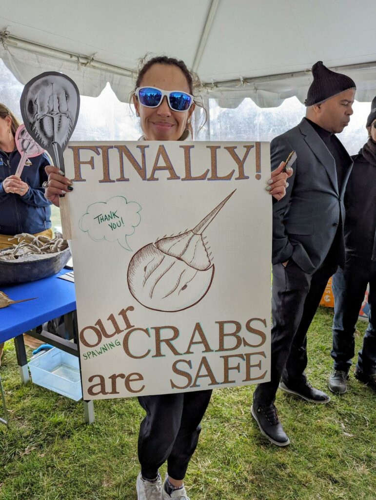 woman holding sign that says finally our crabs are safe